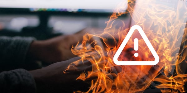 Hände tippen auf einer Tastatur, davor eine Flammenanimation mit einem Warnsymbol