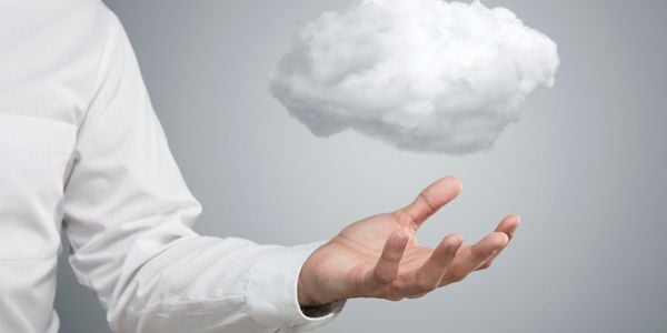 Cloud computing symbol image - businessman holding a symbolic data cloud in his hand against a gray background