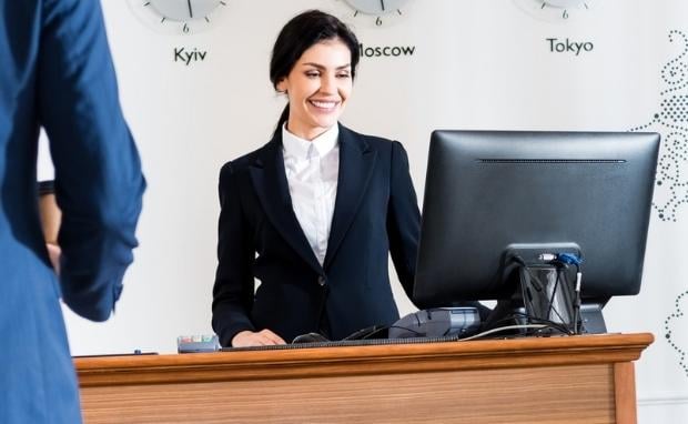 Hotel receptionist with computer - reception situation in international business hotel with world clocks