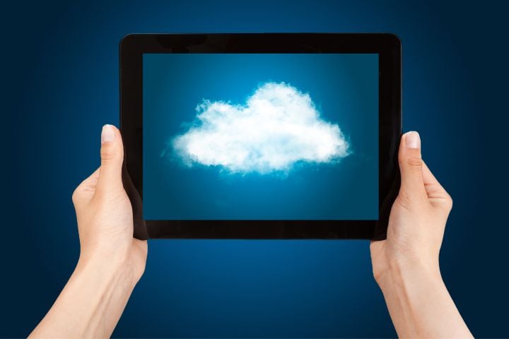 A person is holding a tablet and a cloud with a blue background can be seen on it.